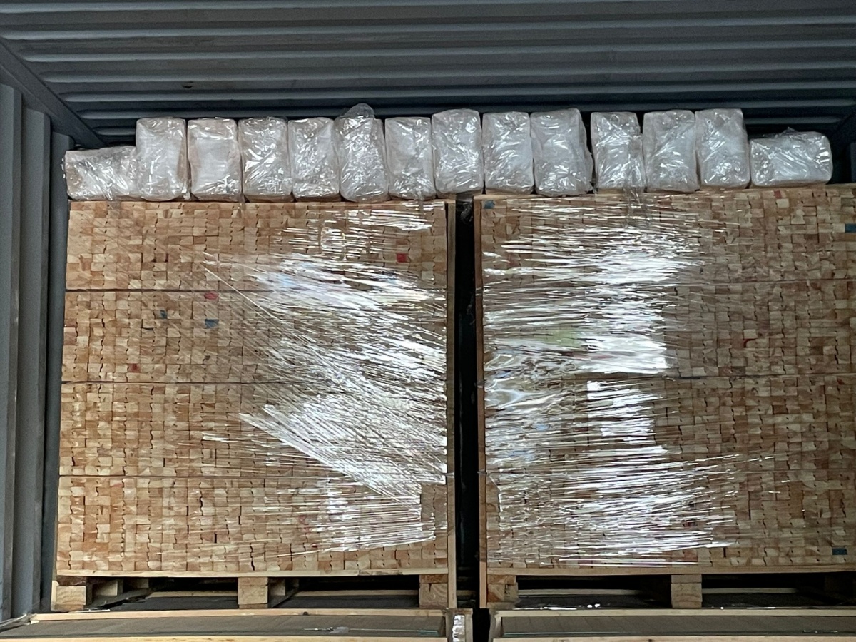Wooden stretcher bars and canvas frames being loaded into an export container
